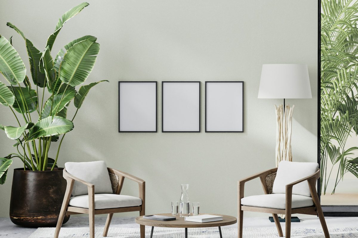 poster frames in room interior with light neutral wall with sunlight and wooden furniture